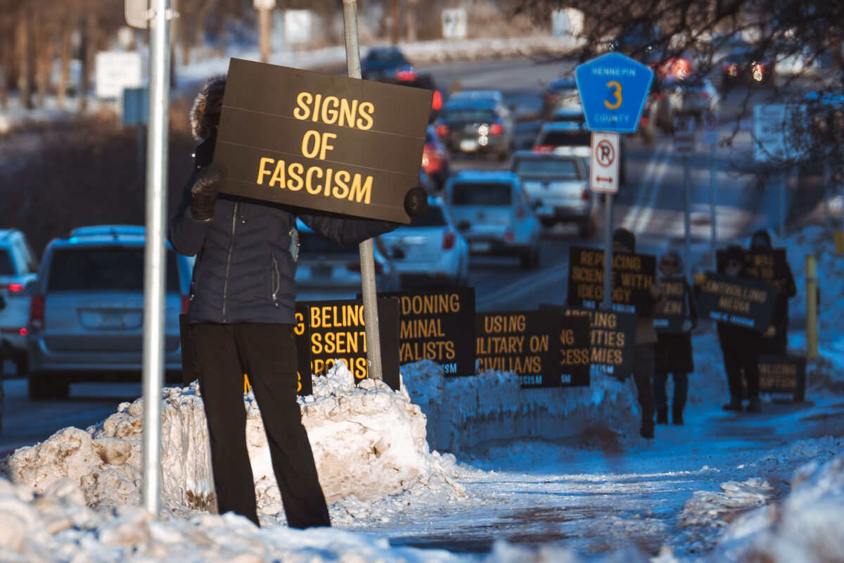 Protesters with illuminated signs on County Road 3 in Hennepin County during a winter roadside protest.