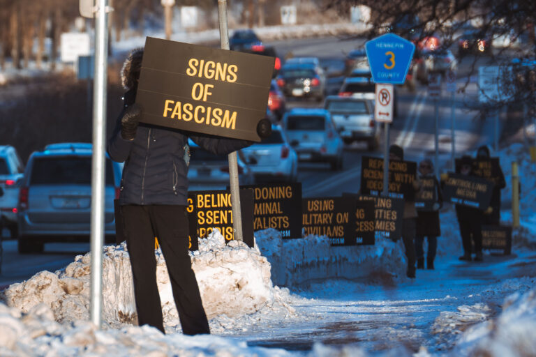 Protesters in the cold on Lake Street 2 Protesters with illuminated signs on County Road 3 in Hennepin County during a winter roadside protest.