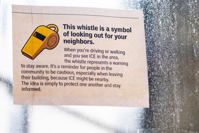 Whistles and Immigration 1 A notice on the doors of the Karmel Mall on Lake Street.This whistle is a symbol of looking out for your neighbors.When you’re driving or walking and you see ICE in the area, the whistle represents a warning to stay aware. It’s a reminder for people in the community to be cautious, especially when leaving their building, because ICE might be nearby. The idea is simply to protect one another and stay informed.
