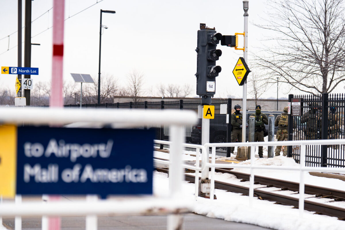Federal agents outside the Whipple federal building as seen from a light rail train station.