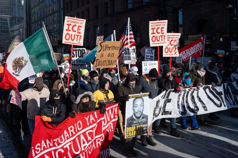 Minneapolis Anti-ICE Protest, January 23 2026 3 Protesters march in downtown Minneapolis on January 23, 2026, holding signs and banners against ICE.