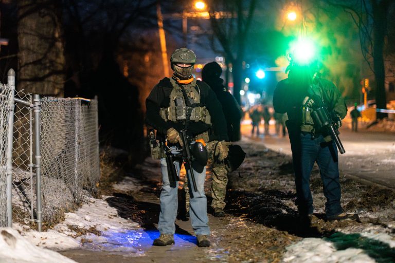 Tactical Officers Patrol Sidewalk, Operation Metro Surge, North Minneapolis 2 Armed federal officers deploy on a snowy North Minneapolis street during Operation Metro Surge.