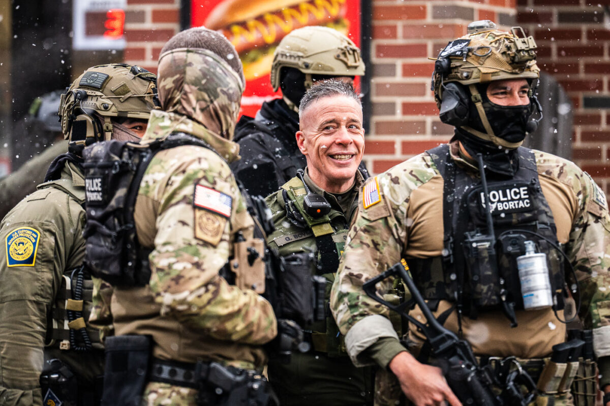 Border Commander Greg Bovino stands outside a South Minneapolis gas station this morning with BORTAC officers in what seemed like an effort to draw more and more people to the scene as other agents shoot high resolution video of the crowd yelling and blowing whistles.
