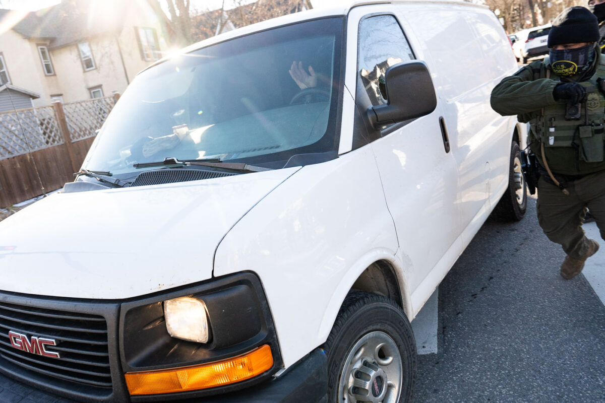 Border Patrol officers attempt to detain someone in a van.