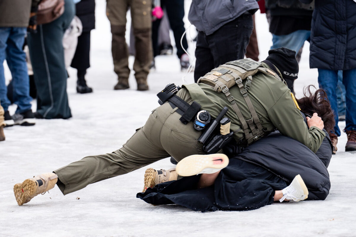 A protester is arrested outside the Whipple Federal Building outside Minneapolis.Protests have gathered outside the fenced in building as hundreds of agents stand outside the fence.
