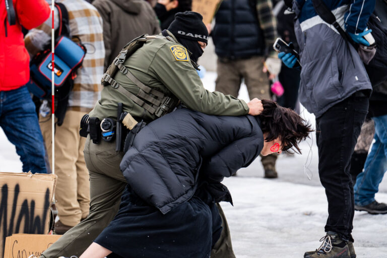 Border Patrol Officer Tackles Protester, Minneapolis 1 A protester is arrested outside the Whipple Federal Building outside Minneapolis.Protests have gathered outside the fenced in building as hundreds of agents stand outside the fence.