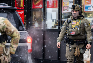 A Border Patrol officer wearing a GoPro on his head goes into a gas station in South Minneapolis on January 21, 2026. This while other agents shoot close up photos of citizens outside the gas station.