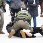 Border Patrol officers and protester in Minneapolis 4 A protester is arrested outside the Whipple Federal Building outside Minneapolis.Protests have gathered outside the fenced in building as hundreds of agents stand outside the fence.