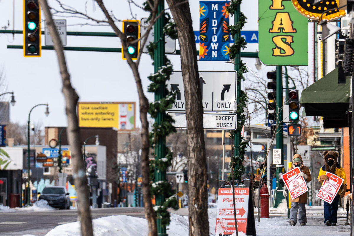 2 people walk down Lake Street in Minneapolis on the morning of January 19, 2026 while holding signs that read "I.C.E. OUT OF MINNEAPOLIS". The sign is in the style of the Minneapolis Snow Emergency route signage.Current temperature: -1°FFeels Like: -18°F