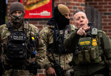 Greg Bovino points at an observer in Minneapolis as he stands with the Border Patrol BORTAC unit outside a South Minneapolis gas station on January 21, 2026.