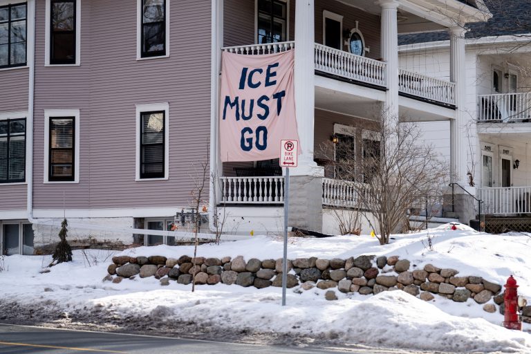 Minneapolis Protest Sign: ICE Must Go 2 A banner reading "ICE MUST GO" hangs on a house in Minneapolis during winter.