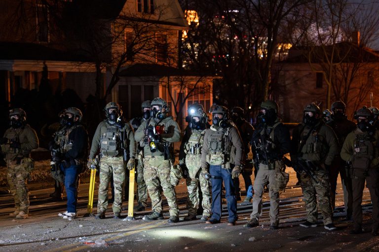 Federal Tactical Officers Line Street, Operation Metro Surge, North Minneapolis 3 Federal officers in tactical gear stand lined up on a Minneapolis street at night during Operation Metro Surge.