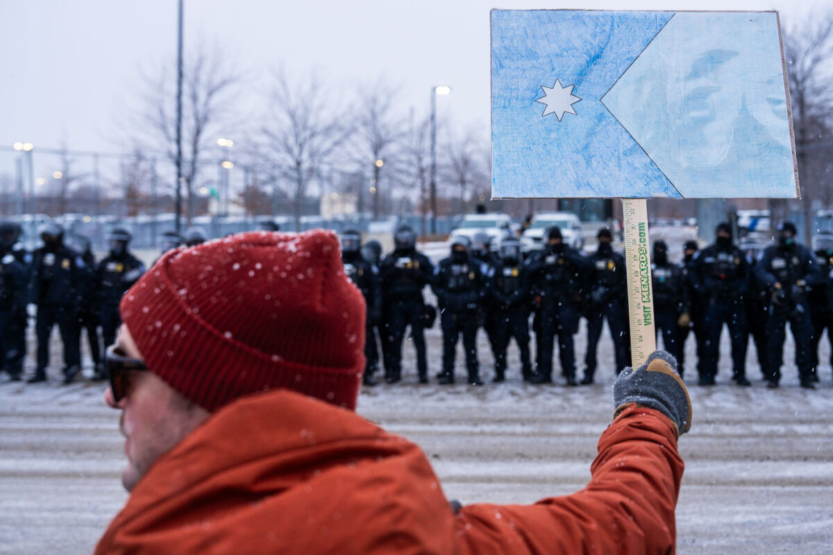 A protester holds up a Minnesota flag protest sign at the Whipple ice facility near Minneapolis on January 16, 2026.