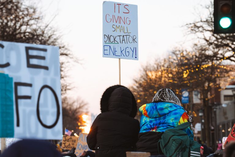 Protesters hold signs after Alex Pretti is killed in Minneapolis