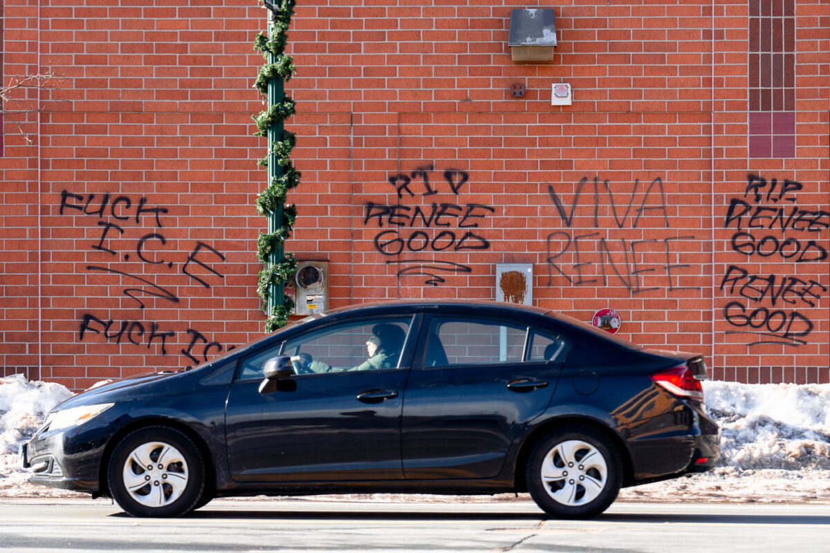 A car drives by a building with graffiti reading "FUCK ICE" "RIP RENEE GOOD" in South Minneapolis on January 9th.