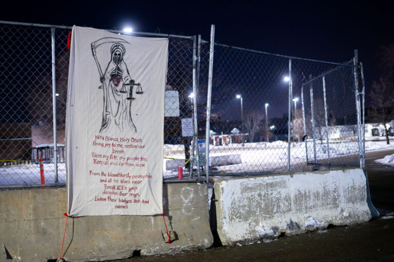 Santa Muerte banner iat Whipple, Minneapolis 1 A banner on the fencing around the Whipple federal building in Minneapolis. The building is used as a ICE detention center and base during current operations in Minnesota. “Nina Blanca Holy DeathBring joy to me, restore our breathBless my fate, my people too,Keep all evil far from view.From the bloodthirsty pedophileand all his allies nearBreak ICE’s grip,dissolve their reign,Leave their badges ash and names”