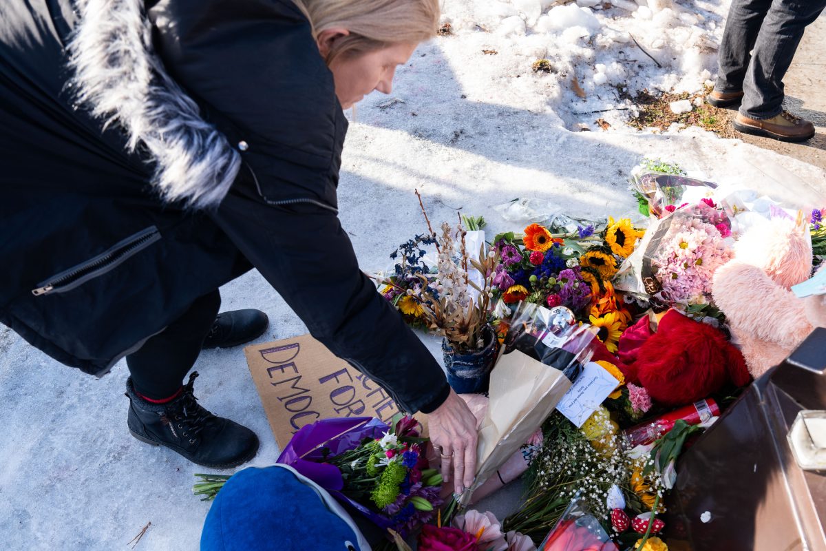 Woman leaves flowers at Renee Good Memorial in Minneapolis