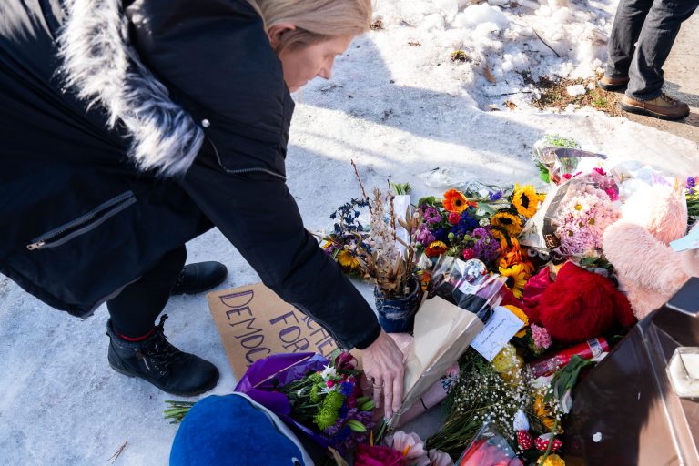 Woman leaves flowers at Renee Good Memorial in Minneapolis 2