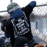 Protester on fence outside Whipple Building 3 This afternoon at the Whipple building where expired dicks were being thrown at ICE vehicles and those believed to be agitators. The building has been used as a “base” for the thousands of federal agents that have arrived in Minnesota as well as a holding center for those detained.The area has been a place of protest since December.