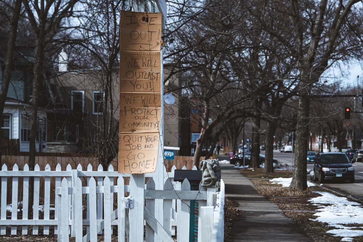 A handmade sign in Minneapolis protests Immigration and Customs Enforcement (ICE) with the message "ICE OUT! WE WILL OUTLAST YOU! WE WILL PROTECT OUR COMMUNITY! QUIT YOUR JOB AND GO HOME!"