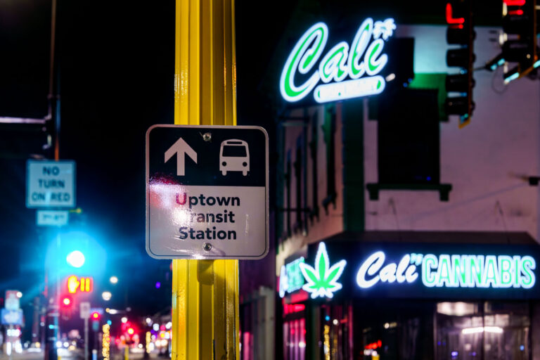 Uptown Transit Station and Cali Cannabis, Minneapolis 4 A sign for the Uptown Transit Station is visible next to a neon sign for Cali Cannabis in Minneapolis, highlighting the mixed-use nature of the neighborhood.