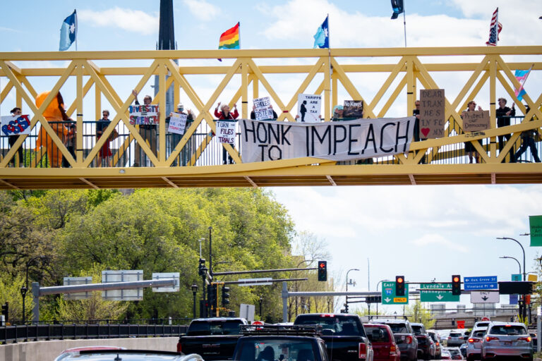 Protesters hold HONK TO IMPEACH sign in Minneapolis 2 Protesters holding signs above Hennepin and Lyndale in Minneapolis