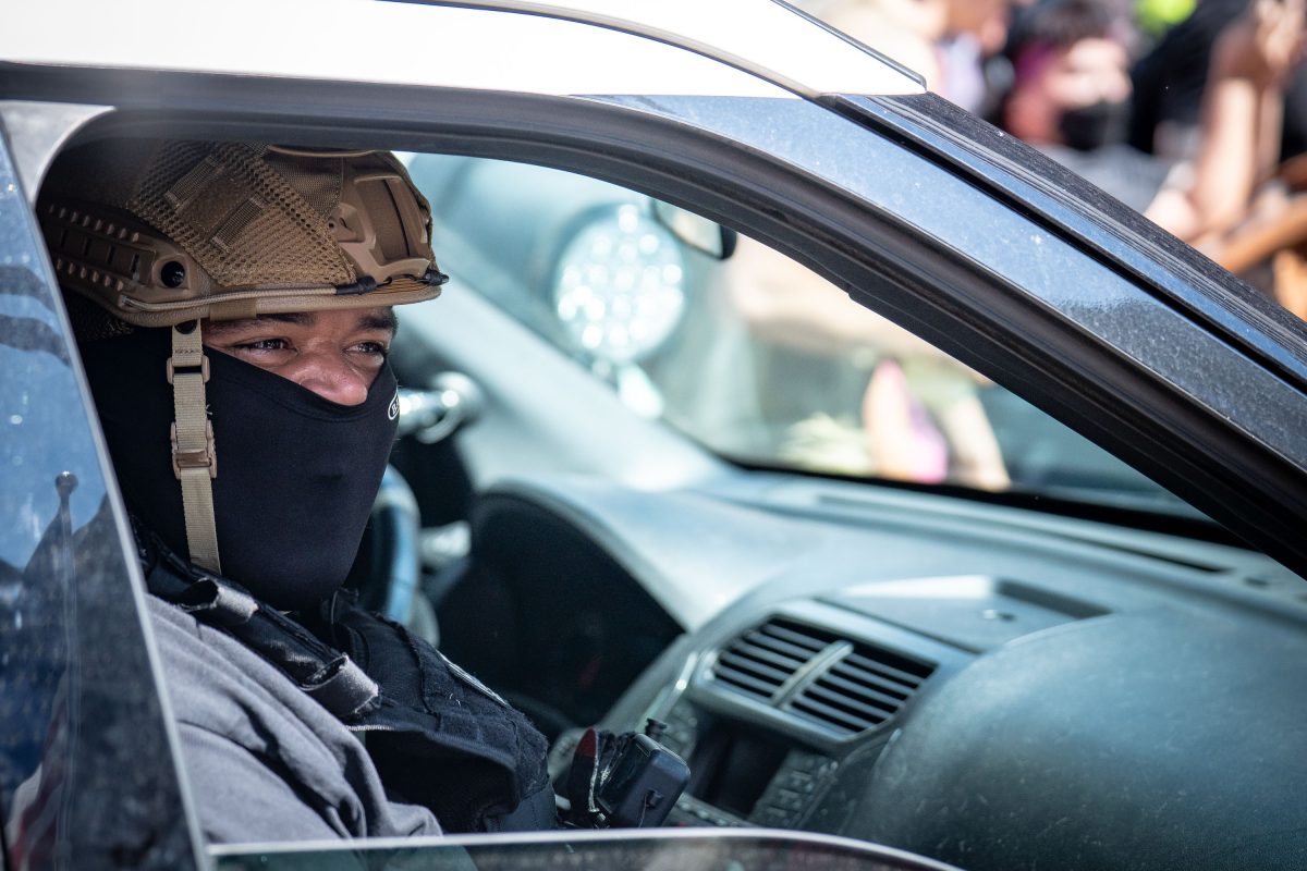 Armed person in tactical gear and mask inside vehicle during confrontation at Minneapolis City Hall.