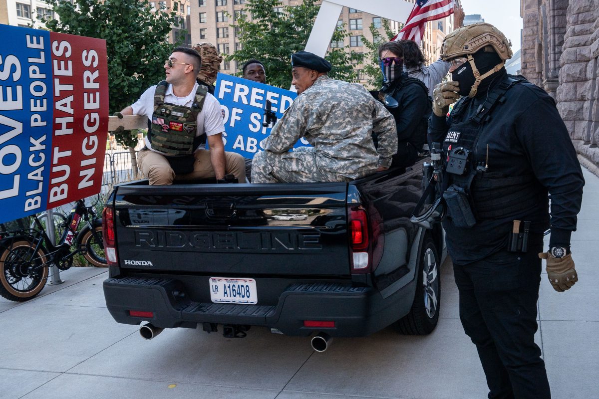 Armed counter-protesters confront a vehicle at Minneapolis City Hall during a white supremacist rally.