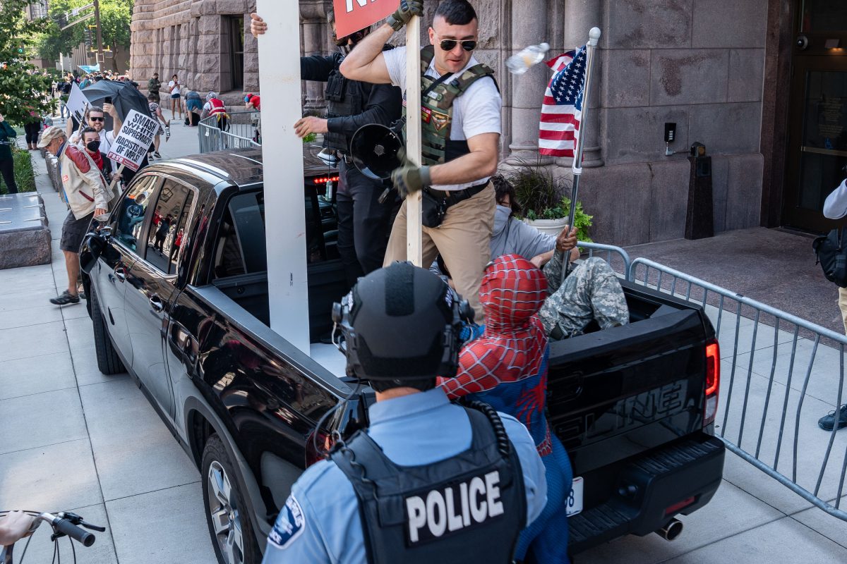 Police officer observes a confrontation between counter-protesters and a vehicle outside Minneapolis City Hall.