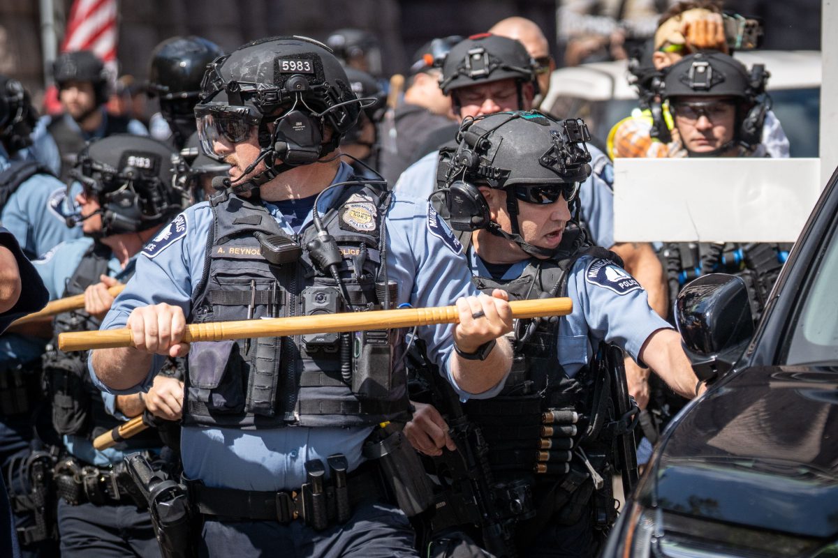 Minneapolis police officers in riot gear confront a vehicle during a white supremacist rally at City Hall.