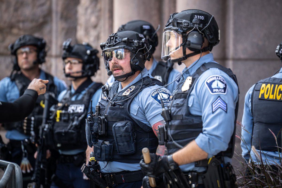 Minneapolis police officers in riot gear stand guard during a white supremacist rally confrontation at City Hall.
