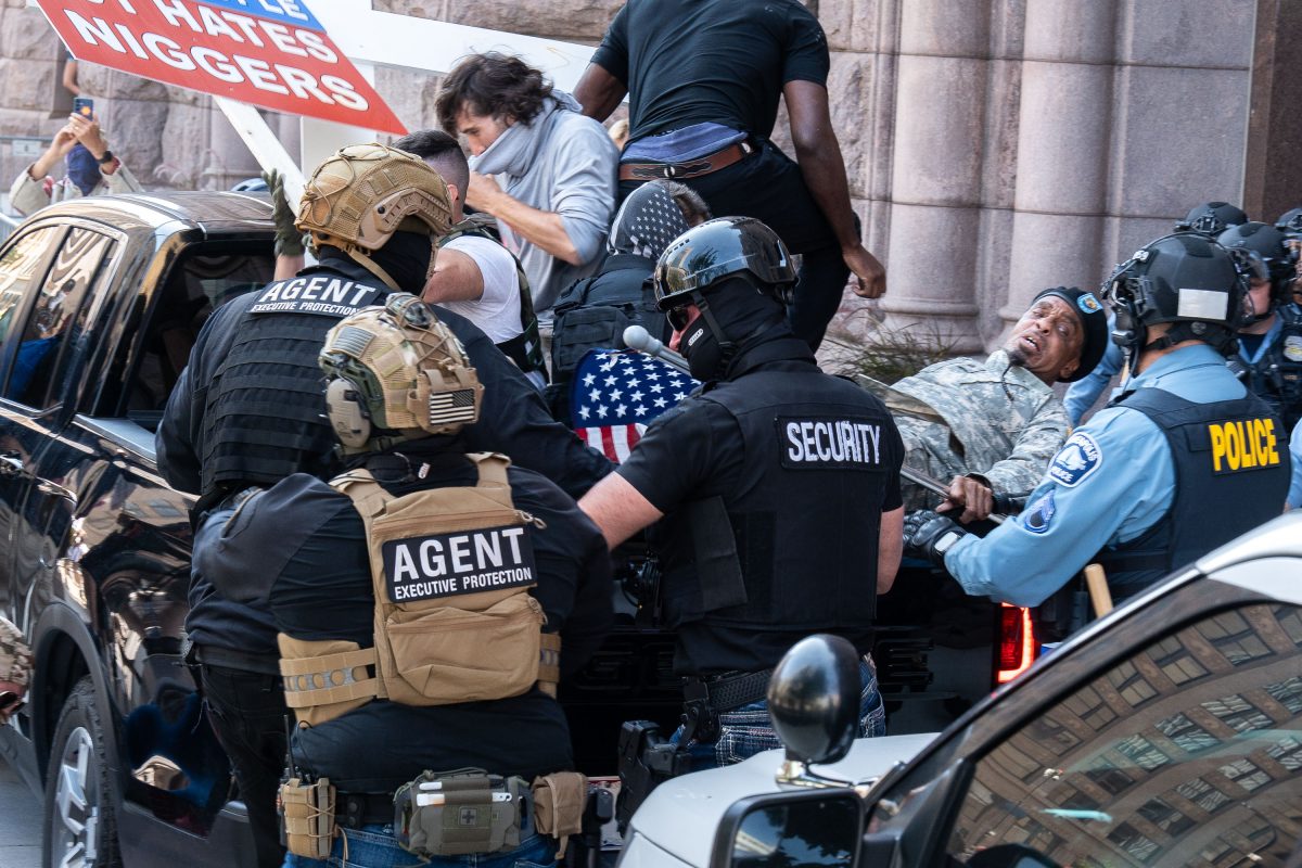Private security and police officers confront counter protesters as a vehicle arrives at Minneapolis City Hall during a white