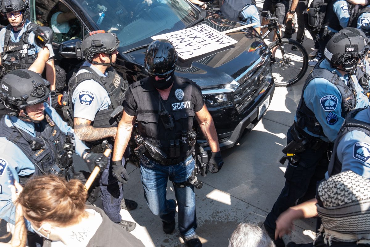 Law enforcement and security personnel surround a vehicle during a confrontation outside Minneapolis City Hall.
