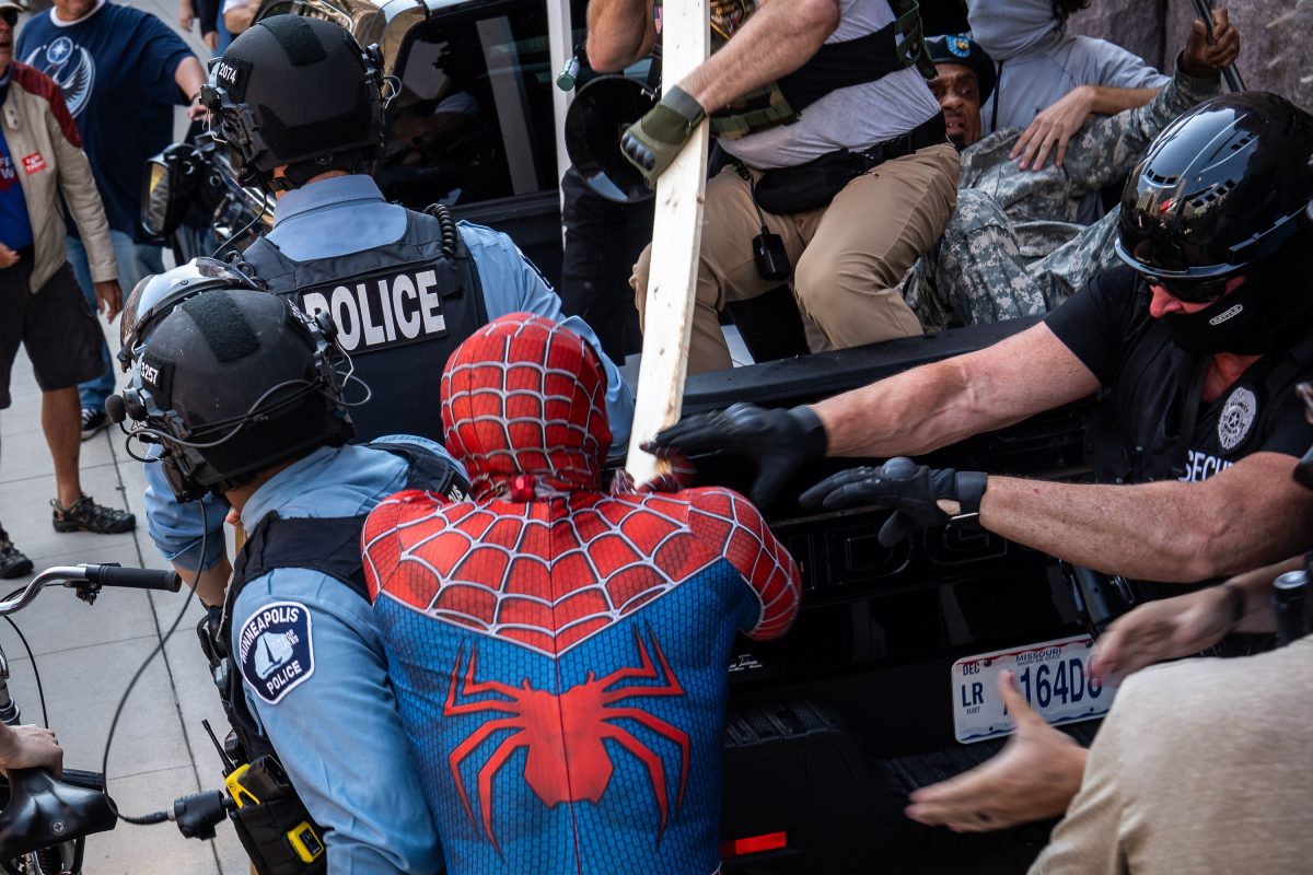 Counter protester dressed as Spiderman and private security at Jake Lang Protest