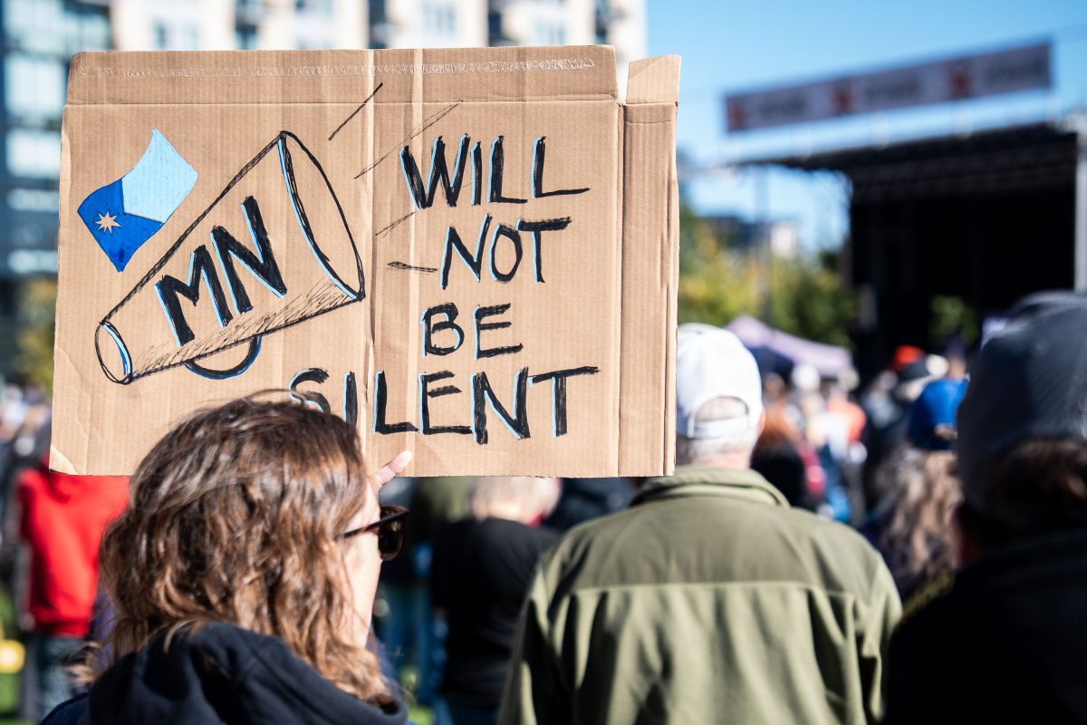 Protester holds cardboard sign reading "MN WILL NOT BE SILENT" at the No Kings rally in Minneapolis.