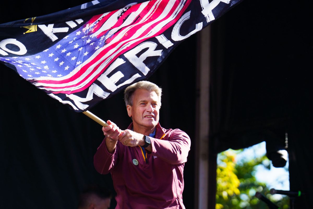 Former Minneapolis Mayor R.T. Rybak holds a flag while speaking at the NO KINGS rally in Minneapolis Commons Park.