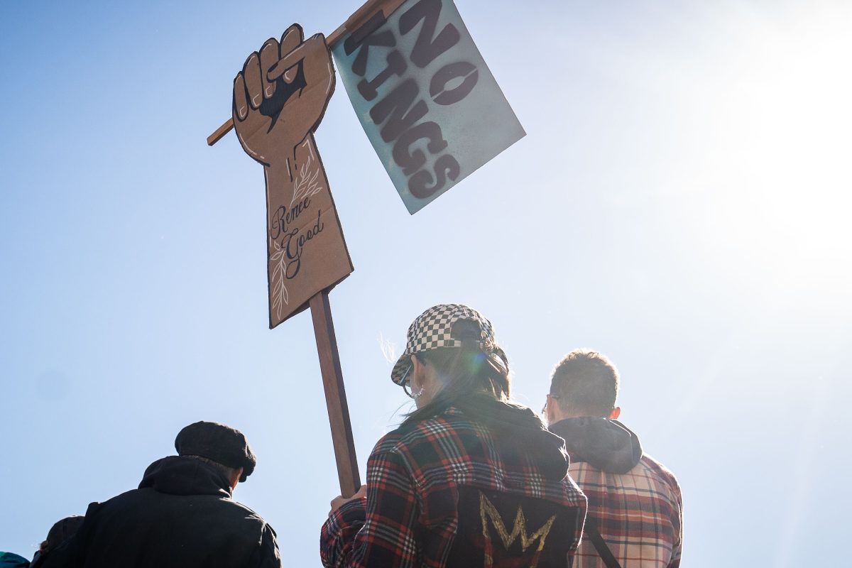 Protesters hold a raised fist sign and banner at the NO KINGS rally in Minneapolis Commons Park.