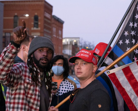 Two men wearing "Make America Great Again" hats disrupt a housing protest. Two men wearing "Make America Great Again" hats disrupt a housing protest.