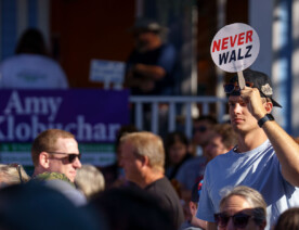 A man holds up a "Never Walz" sign on a stick at the Minnesota State Fair outside where Governor and Vice Presidential Candidate Tim Walz was going to make an appearance.