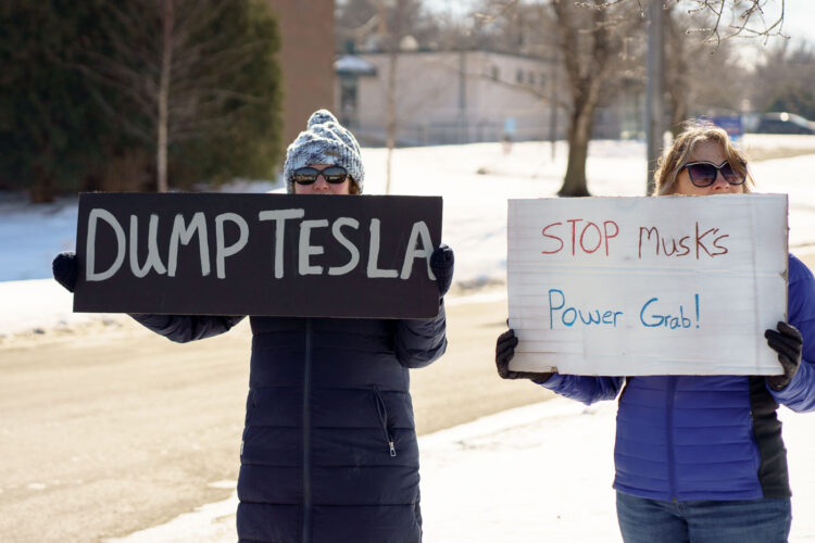 Protesters hold signs that read "Dump Tesla" "Stop Musk's Power Grab!" at a "Tesla Takedown" protest in front of a Tesla facility in Minneapolis on February 22, 2025. Protesters hold signs that read "Dump Tesla" "Stop Musk's Power Grab!" at a "Tesla Takedown" protest in front of a Tesla facility in Minneapolis on February 22, 2025.