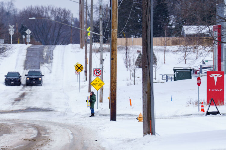 Protester outside a Telsa showroom in Minneapolis (Golden Valley) with staged Golden Valley police squad cars. Protester outside a Telsa showroom in Minneapolis (Golden Valley) with staged Golden Valley police squad cars.