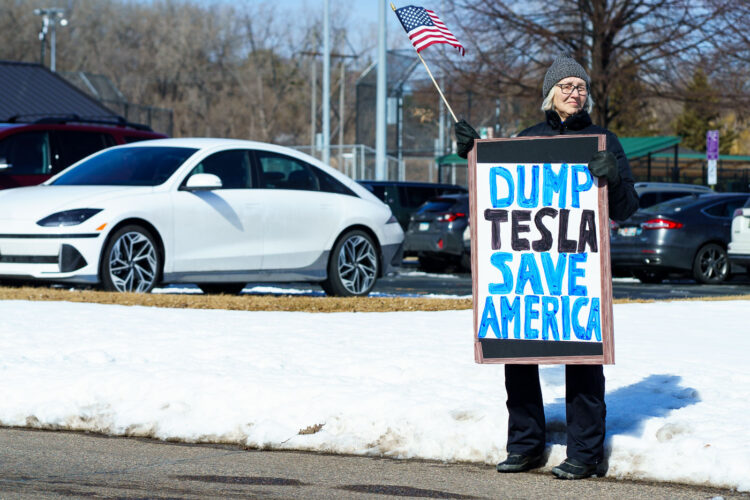Protester holds a sign that reads "Dump Tesla Save America". Seen at a Tesla facility just outside of Minneapolis (Golden Valley) on March 8, 2025.This is the 4th week in a row protesters have gathered here as part of the nationwide Tesla Takedown organizing. Protester holds a sign that reads "Dump Tesla Save America". Seen at a Tesla facility just outside of Minneapolis (Golden Valley) on March 8, 2025.This is the 4th week in a row protesters have gathered here as part of the nationwide Tesla Takedown organizing.
