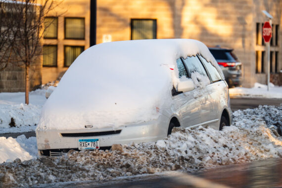A car parked behind snowbanks with a ticket for violation of snow emergency stuck in the window. A car parked behind snowbanks with a ticket for violation of snow emergency stuck in the window.